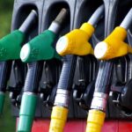 Close-up of gas pump nozzles with green and yellow handles.